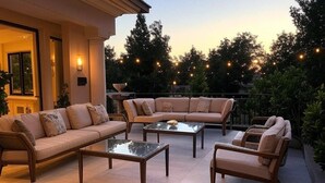 Un espace extérieur aménagé en terrasse, avec un canapé beige, deux fauteuils et une table basse.