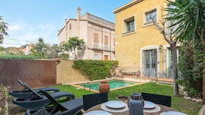 Um pátio com piscina, móveis de exterior e um edifício com varanda.