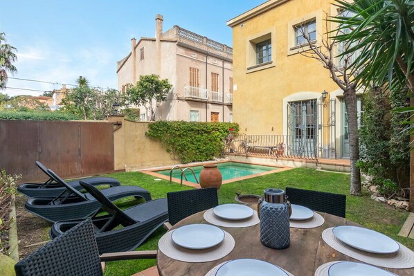 A patio with a pool, outdoor furniture, and a building with a balcony.