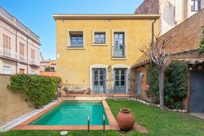 A yellow building with a swimming pool, a door, and a window.