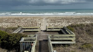 Ein Strand mit Holzstegen, die zu einem Sandbereich führen.