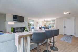 Een moderne keuken met een eethoek, met een kookeiland inclusief barstoelen, een open haard en grote ramen.