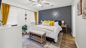 Ein Schlafzimmer mit Bett, Nachttisch und Deckenventilator.