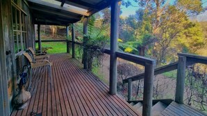 Eine Holzterrasse mit Stühlen und einem Tisch, mit Blick auf ein bewaldetes Gebiet.