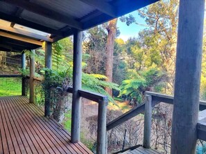 A wooden deck with a view of a forested area. - Forget Me Not Cottages-Music Room (Warburton)