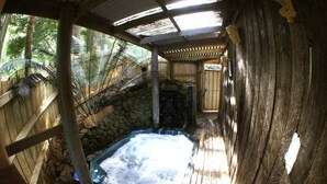 Ein Bereich mit Whirlpool, Steinwand, Holzterrasse und überdachter Dachkonstruktion.