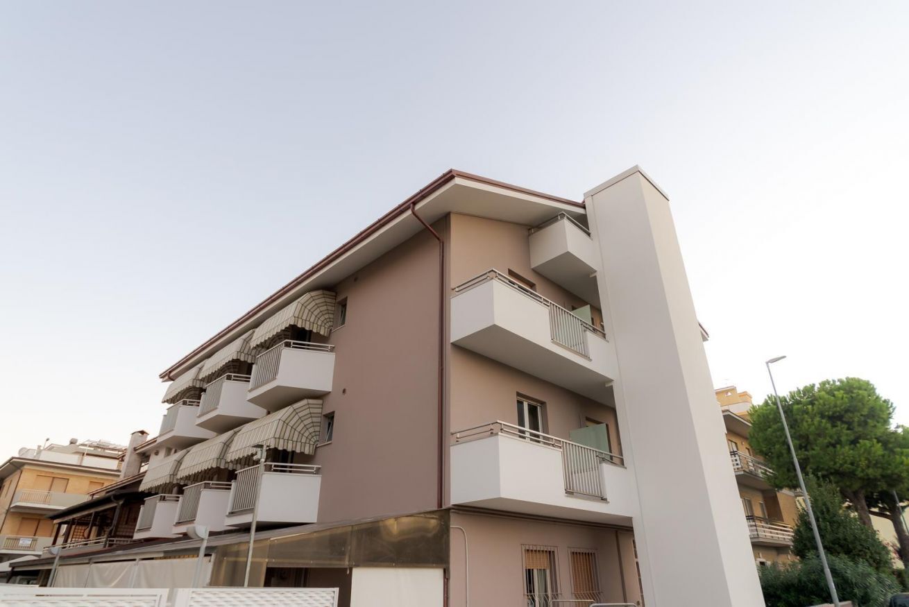 A multi-story residential building with balconies, a flat roof, and a beige facade.
