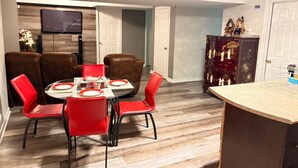 A dining area with a round table, red chairs, and a dark wooden cabinet with decorative items.