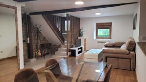 Una sala de estar moderna con una escalera, una mesa de centro de cristal, un sofá y una chimenea.