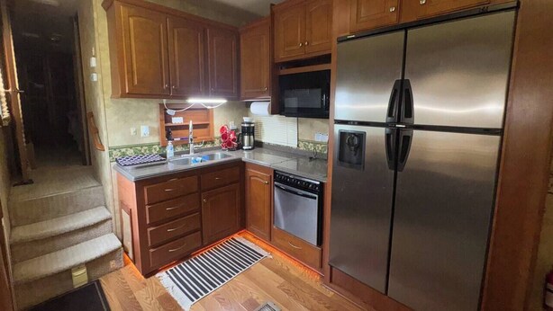 A compact kitchen with wooden cabinets, stainless steel appliances, and a built-in microwave. - Spacious RV with AC in charming Holly Beach (Lake Charles)