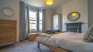 Een slaapkamer met een houten bed, een dressoir, een spiegel en een open haard.
