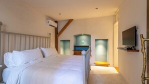 Ein Schlafzimmer mit einem Bett, einem an der Wand montierten Fernseher und einer Treppe zu einer oberen Ebene.