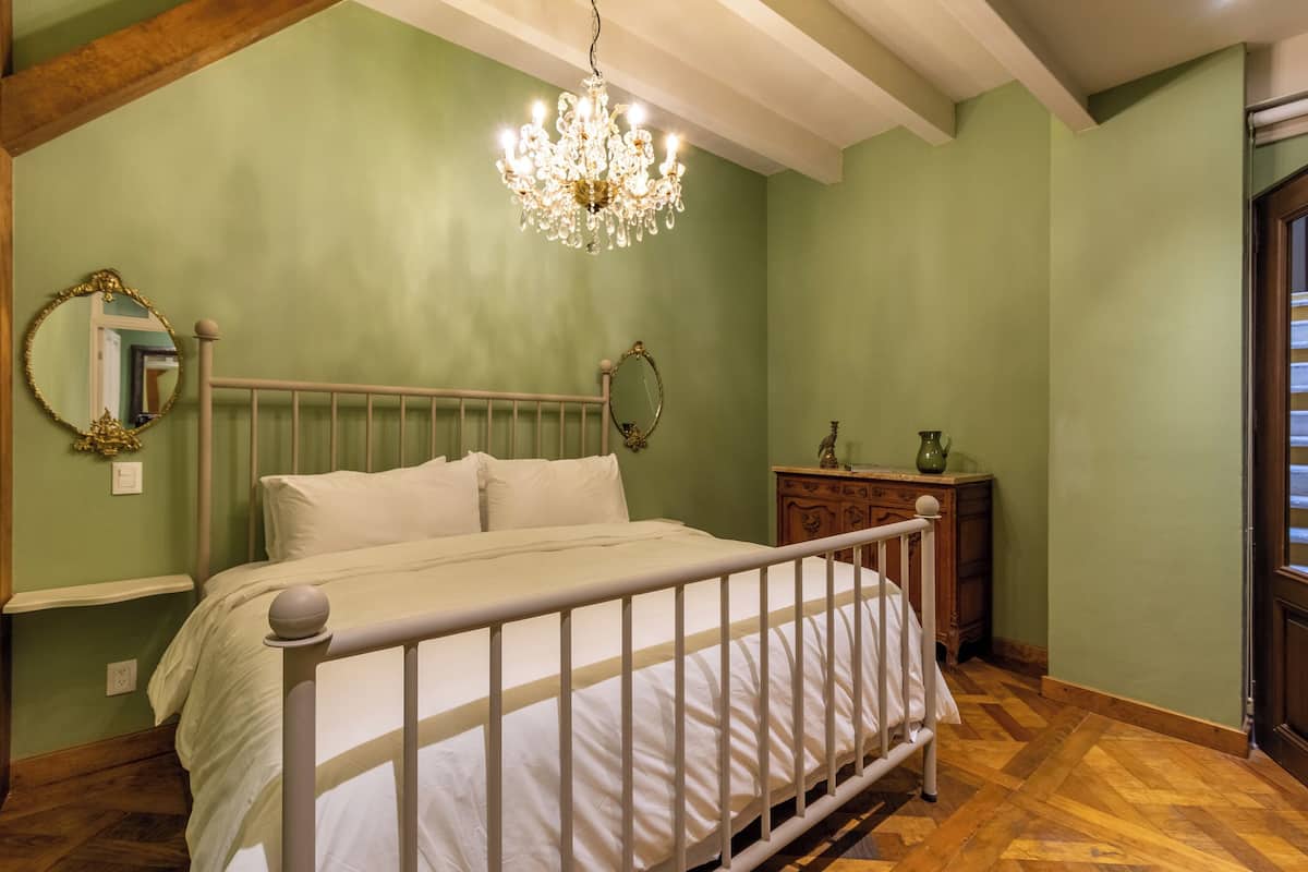 Un dormitorio con cama, candelabro, cómoda y espejo.