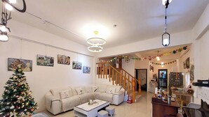 A living room with a sofa, coffee table, and a Christmas tree. There is a staircase leading to another room. - Bliss inn (Yuli)