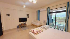 A bedroom with a bed, a TV, a sofa, a balcony with a view, and a ceiling light fixture. - Bliss inn (Yuli)