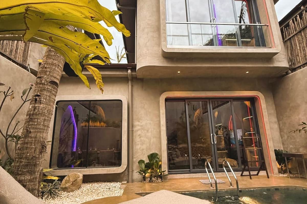 Una casa moderna con piscina, ventanas amplias y una palmera.