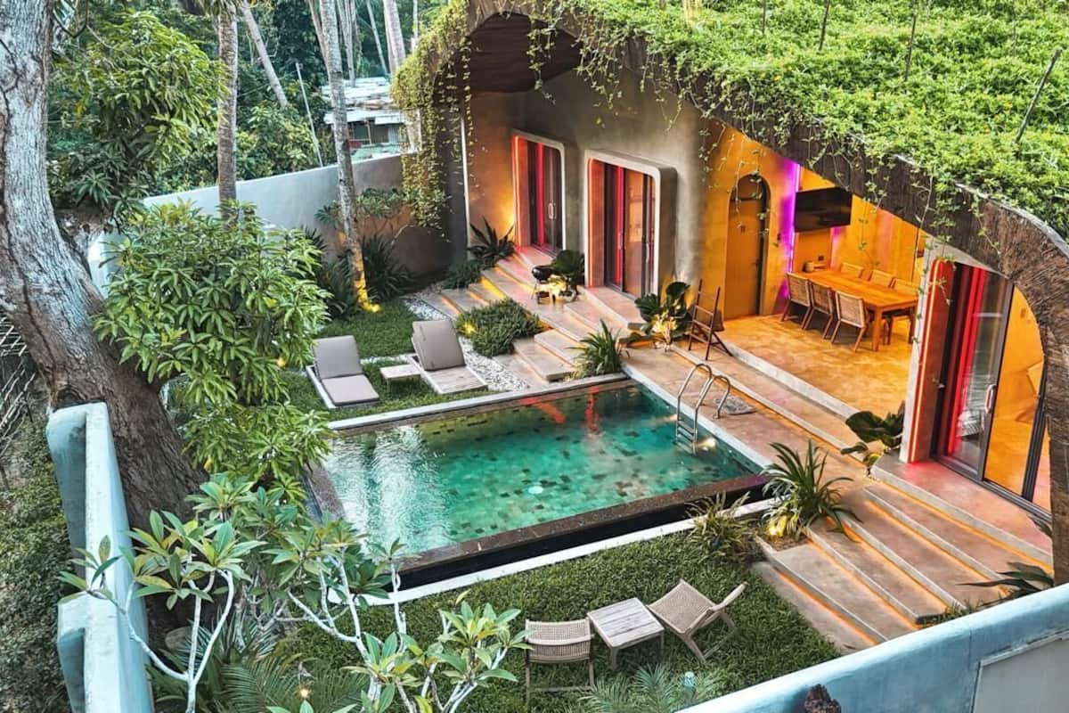 Una casa moderna con piscina, mobiliario exterior y un patio cubierto.