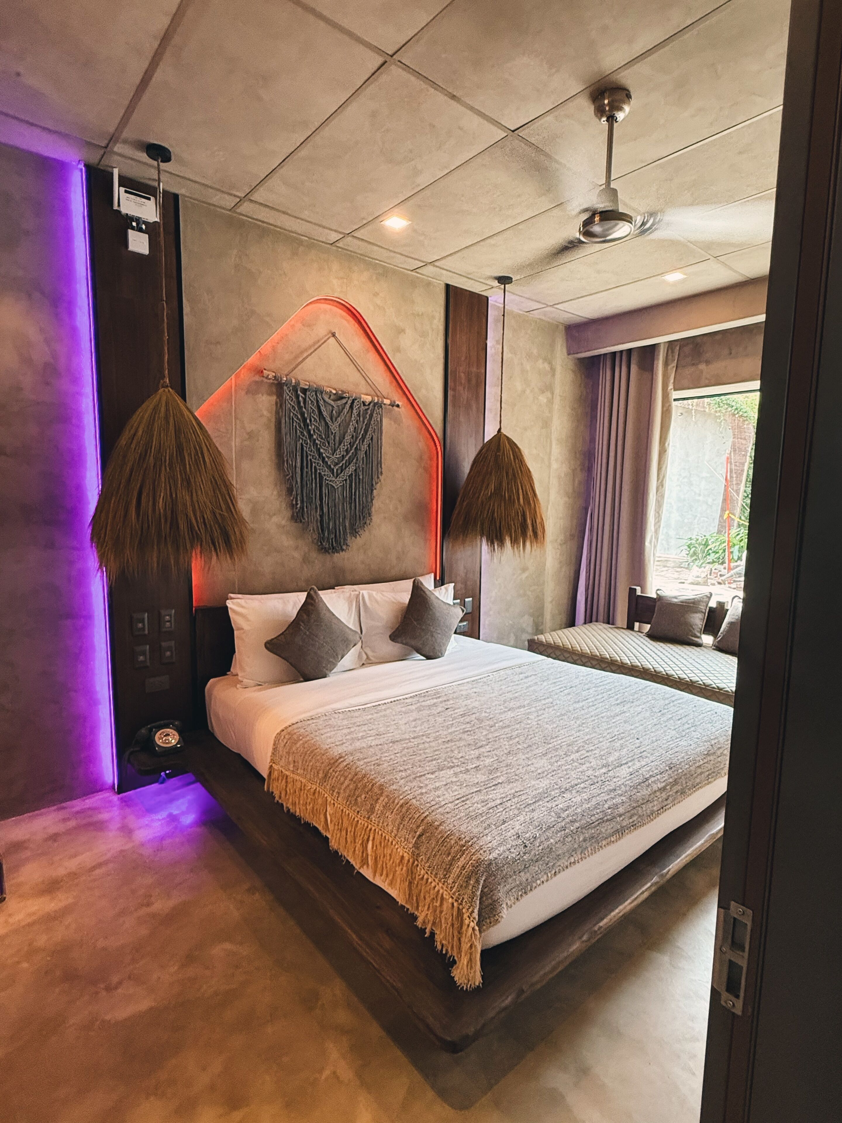 A modern bedroom with a large bed, two hanging lamps, and a ceiling fan.
