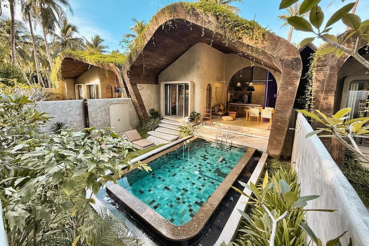 Zona de piscina con solárium empedrado, un espacio de descanso cubierto y vistas a la piscina.