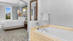 Ein Hotelzimmer mit einem großen Bett, einem Badezimmer mit einer Badewanne und Blick auf die Berge.