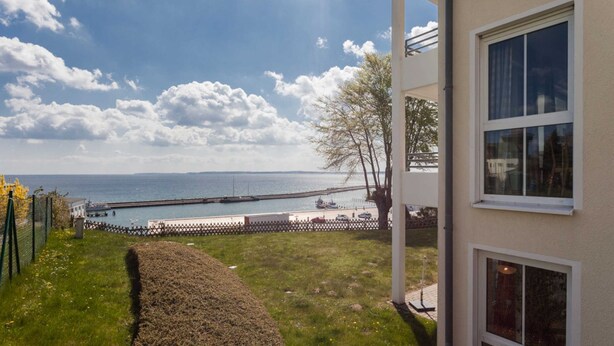 A coastal view from a building with a paved pathway leading to a dock.