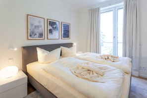 Et hotelværelse med en stor seng, to sengeborde og et vindue med gardiner.