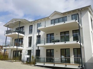 Un immeuble résidentiel moderne à plusieurs étages, doté de balcons et de grandes fenêtres.