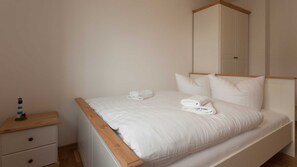 Ein Schlafzimmer mit Bett, Nachttisch, Kleiderschrank und einer kleinen Dekoration.