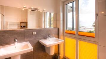 Ein modernes Badezimmer mit zwei Waschbecken, einem großen Spiegel und einem Fenster mit Jalousien.