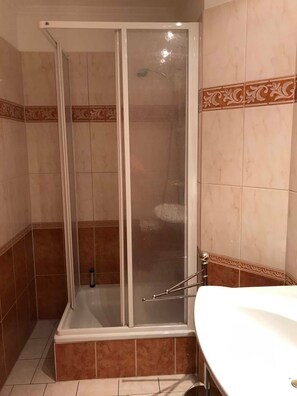 Box doccia con porta in vetro, vasca e lavabo con portasciugamani.