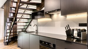 Une cuisine moderne dotée d’un four encastré, d’un évier en acier inoxydable et d’un escalier en bois.