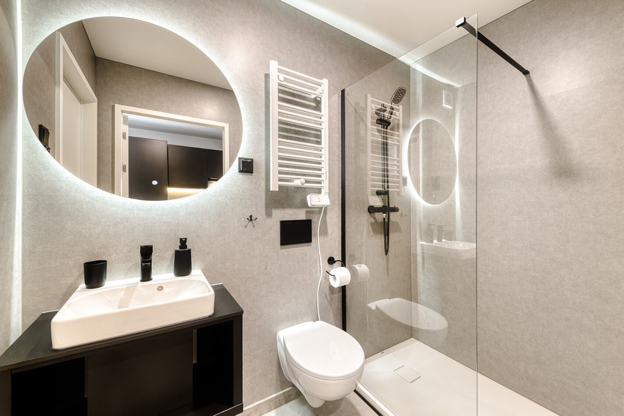 A modern bathroom with a glass shower enclosure, a white sink, and a toilet.