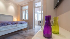 Une chambre à coucher avec un lit, un téléviseur fixé au mur et deux vases posés sur une table de chevet.