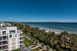 A modern building with multiple balconies overlooking a beach and the sea.