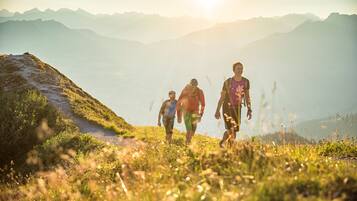 Eine Gruppe Wanderer auf einem Bergpfad mit Blick auf ferne Berge und einen klaren Himmel.
