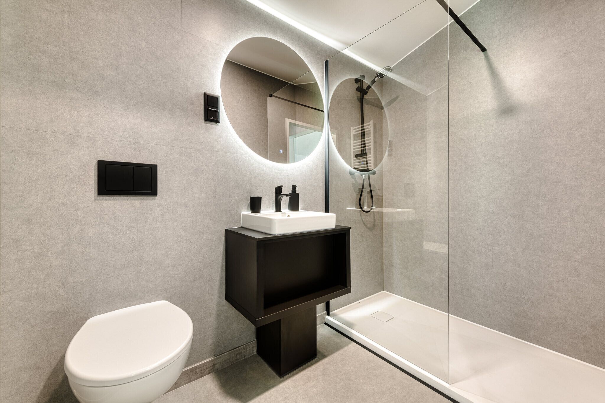 A modern bathroom with a toilet, a sink with a mirror, and a glass-enclosed shower.