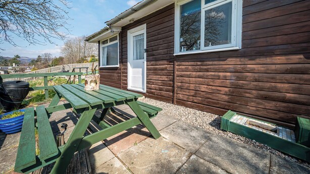 A wooden cabin with a picnic table and a small garden area. - 2 Bed Chalet - Sleeps 4 - River and mountain views (Strathpeffer)