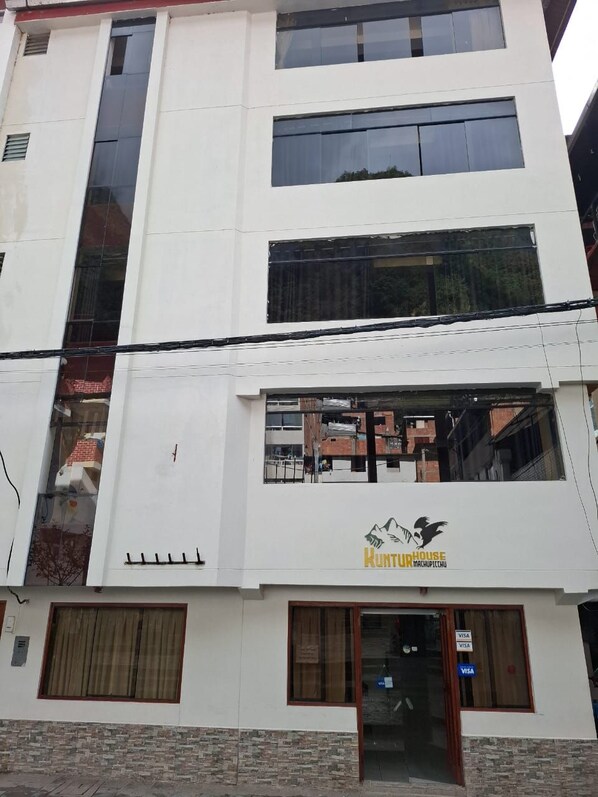 Un edificio de varios pisos con un letrero que dice "Hunting House Machupicchu".