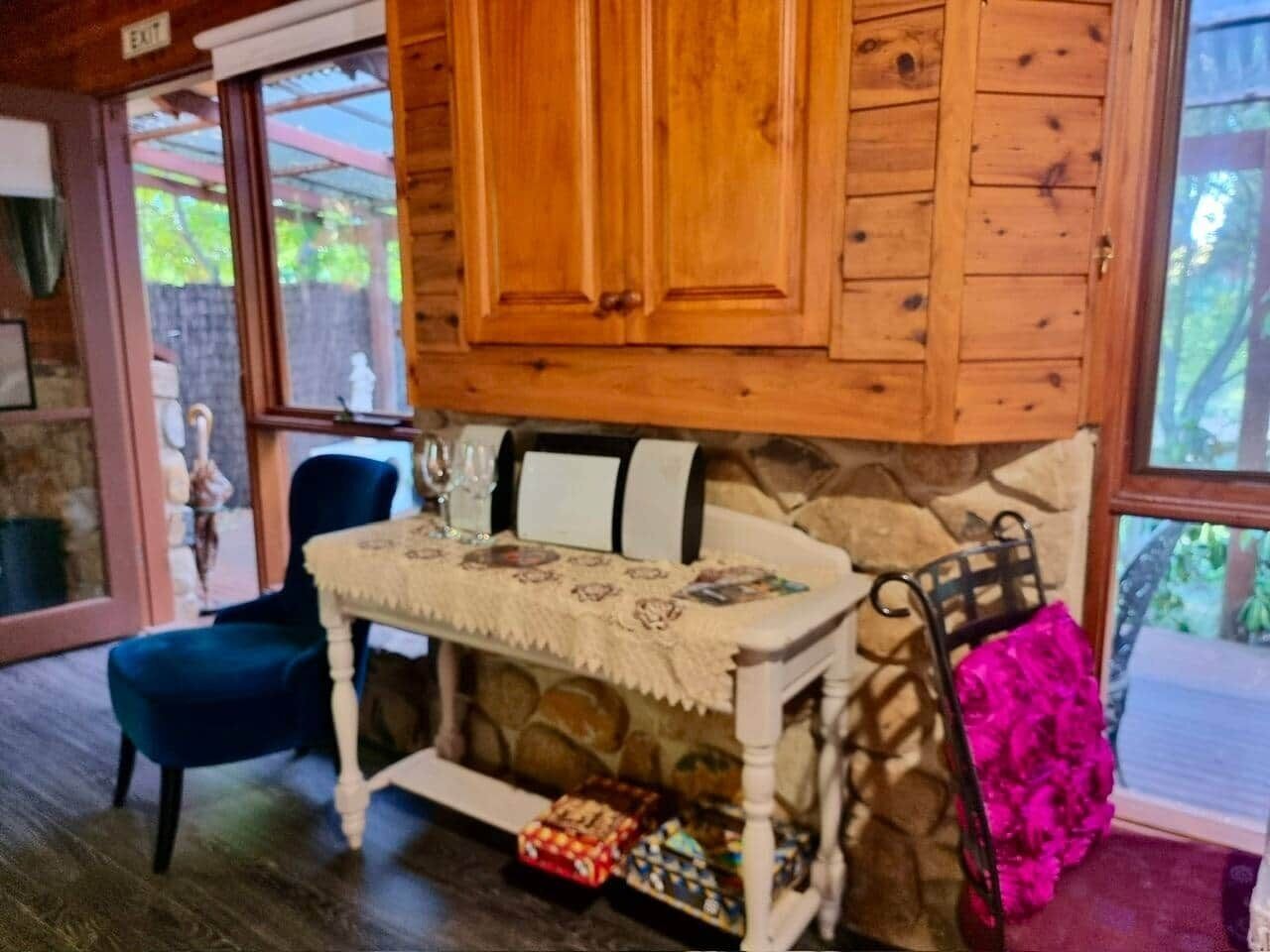 Una habitación acogedora con chimenea de piedra, una mesa de comedor con mantel de encaje y una silla azul.
