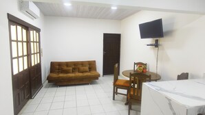A living room with a sofa, a dining table with chairs, a TV mounted on the wall, and a door. - Charming 1-bedroom apartment in lovely Santa Cruz with WiFi, AC (Santa Cruz de la Sierra)