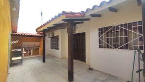 A covered patio area with a tiled floor, a small table, and a chair. - Charming 1-bedroom apartment in lovely Santa Cruz with WiFi, AC (Santa Cruz de la Sierra)