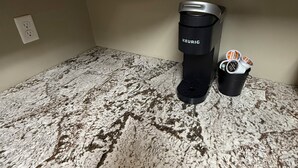 A kitchen counter with a Keurig coffee maker and a cup of coffee pods.