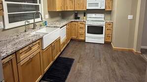 A kitchen with wooden cabinets, a granite countertop, a double oven, and a microwave.