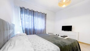 A bedroom with a bed, a television, and a window with curtains. - Miramare 3 LUX - Total Sea View, Andora, Italy (Andora)