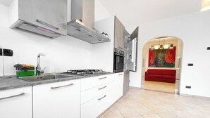 A modern kitchen with white cabinets, a gas stove, and a stainless steel sink. - Miramare 3 LUX - Total Sea View, Andora, Italy (Andora)