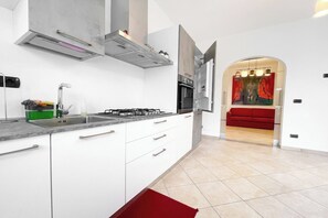 A modern kitchen with white cabinets, a gas stove, and a stainless steel sink. - Miramare 3 LUX - Total Sea View, Andora, Italy (Andora)