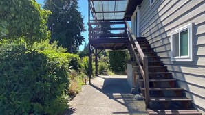 Una propiedad residencial con una escalera de madera que conduce a un espacio al aire libre cubierto.