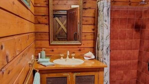 Une salle de bain en bois avec un lavabo, un miroir et une douche.
