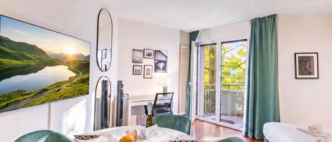 A modern hotel room with a dining area, a bed, and a balcony with a view of the outdoors.