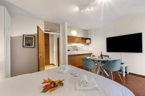 A hotel room with a bed, a TV, a dining area, and a kitchenette. - La Perla Sul Lago, Paradiso (Lugano), Switzerland (Paradiso (Lugano))